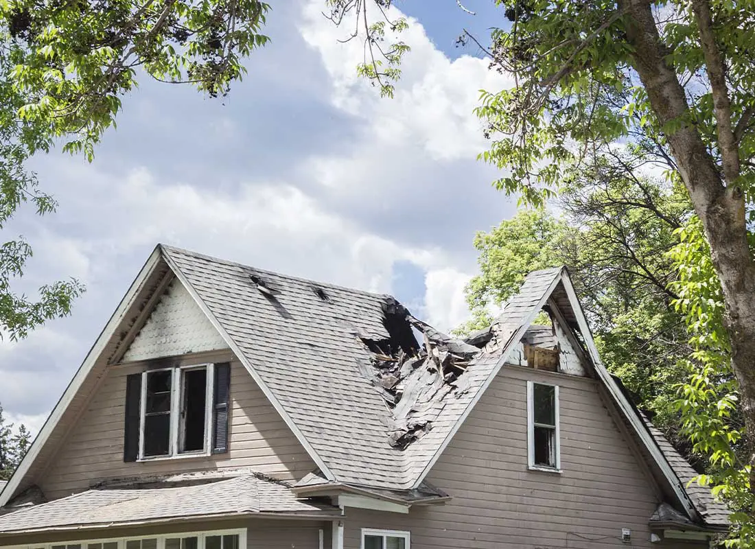 Difference-in-Conditions-Insurance-Close-up-of-the-Roof-of-a-House-That-Has-Collapsed-under-Blue-Sky-with-Clouds-on-a-Sunny-Day