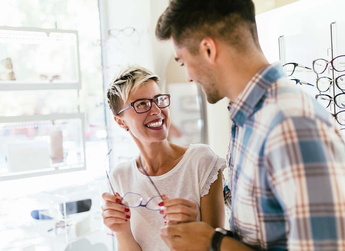 Individual-Vision-Insurance-Smiling-Young-Couple-after-an-Eye-Exam-and-Trying-on-Glasses-before-Making-a-Purchase