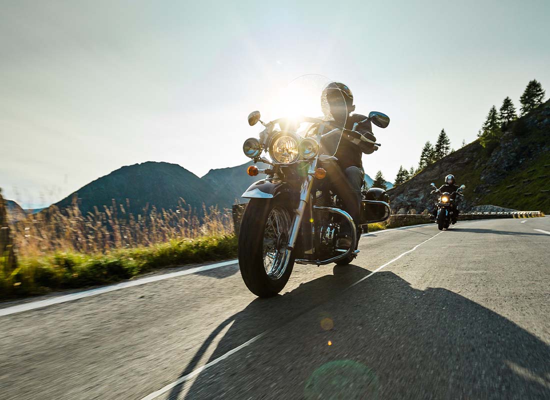 Motorcycle-Insurance-Motorcycle-Driver-Riding-Along-a-Scenic-Highway-at-Dusk-With-Mountains-in-the-Distance