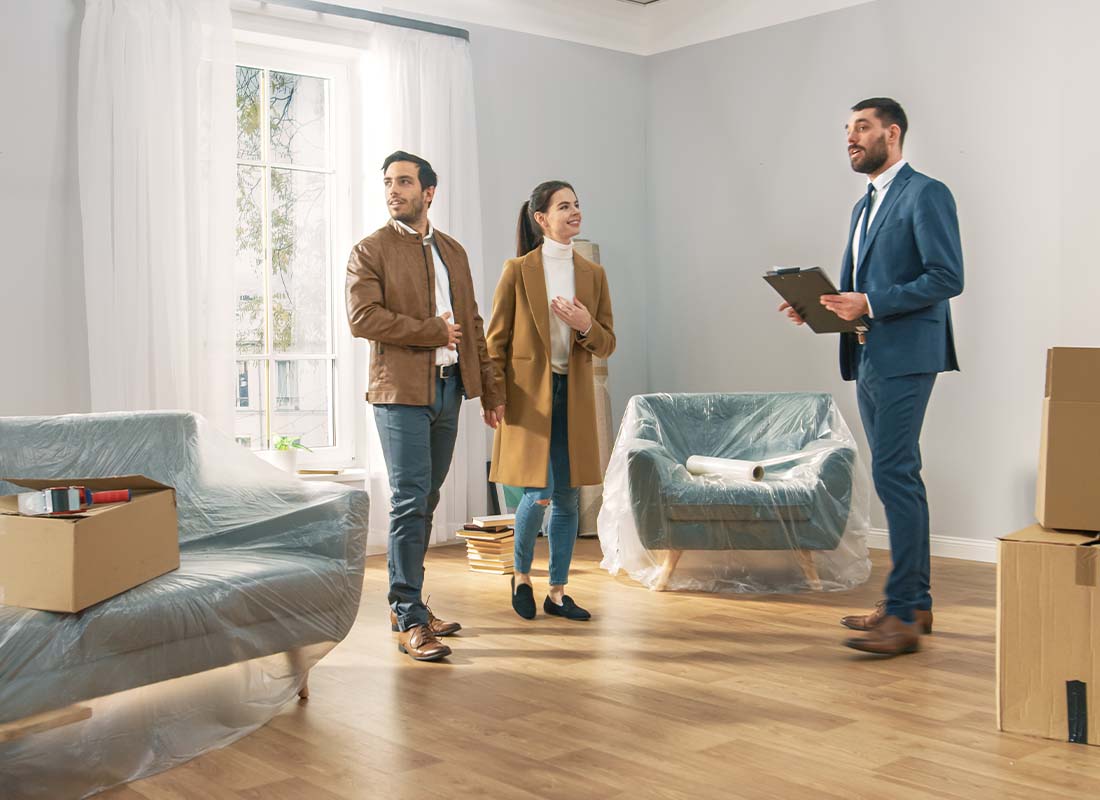 Rental-Property-Insurance-A-Professional-Real-Estate-Agent-Shows-a-Spacious-Bright-Apartment-with-Big-Windows-to-a-Young-Couple