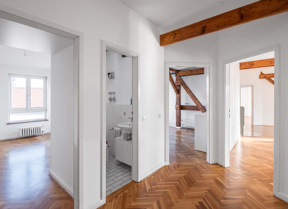 Vacant-Home-Insurance-Hardwood-Floors-and-Exposed-Wooden-Beams-of-a-Vacant-Penthouse-Apartment-after-a-Renovation-with-Multiple-Rooms-and-View-of-Bathroom